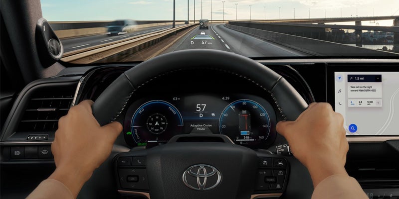 Driver’s hands on the steering wheel of a 2025 Toyota Crown, displaying a digital speedometer and dashboard