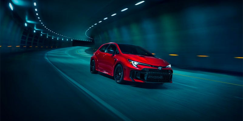 Red 2025 Toyota GR Corolla driving through a dimly lit tunnel at night