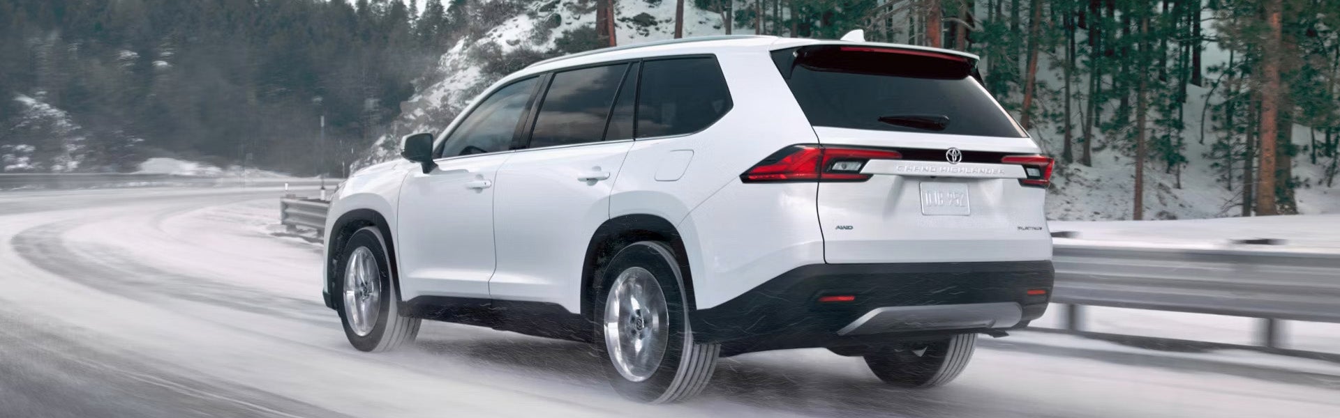 Rear view of a 2025 Toyota Grand Highlander driving on a snowy mountain road.