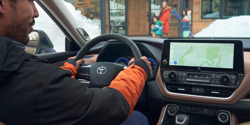 Driver operating the 2025 Toyota Grand Highlander, showcasing the steering wheel and touchscreen navigation system