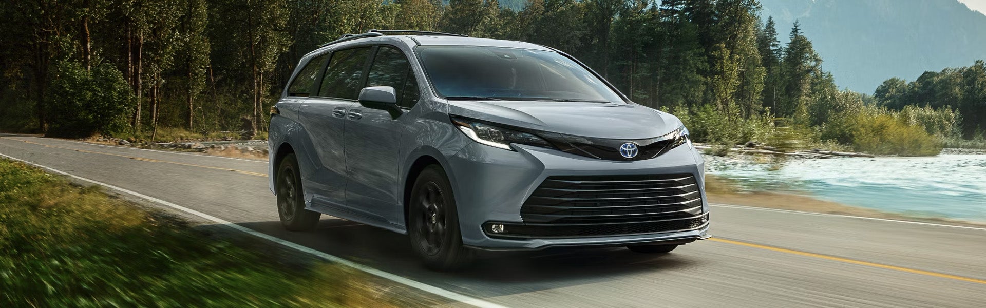 2025 Toyota Sienna minivan cruising along a lakeside road.