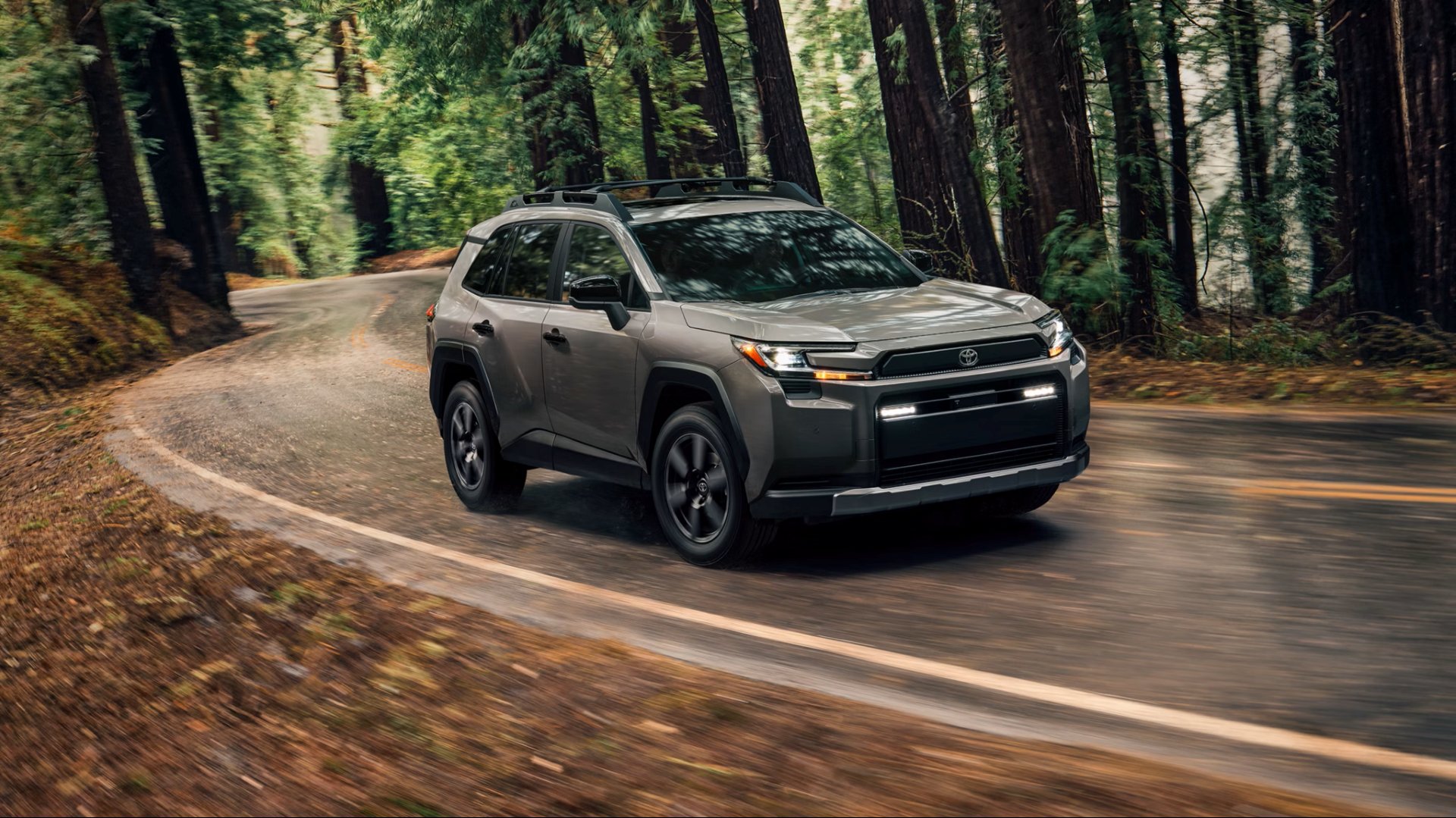 Gray 2026 Toyota RAV4 taking a turn on a forest road